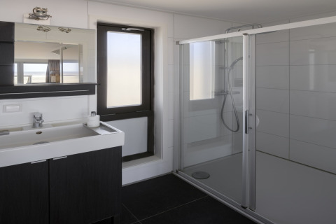 Modernes Badezimmer mit Glasdusche und Waschtisch in einem Strandhaus im Resort Hoek van Holland, Niederlande.