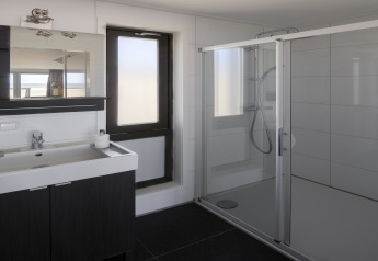 Baño moderno con ducha de vidrio y lavabo en una casa de playa en Resort Hoek van Holland, Países Bajos.