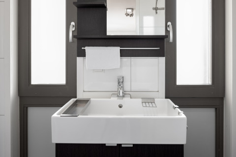 Modernes Waschbecken mit Spiegel und Handtuch im Badezimmer des Resorts Hoek van Holland, Niederlande.
