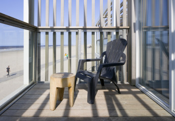 Balcón en Resort Hoek van Holland, Países Bajos, con silla negra y vista a la playa de arena.
