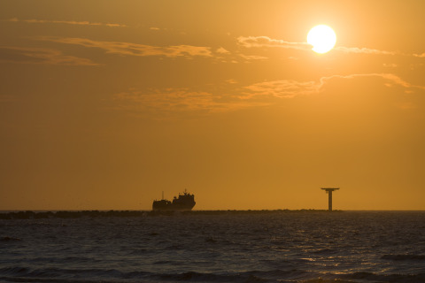 Sonnenuntergang am Meer bei Resort «Hoek van Holland» in den Niederlanden, mit Schiff und Turm.