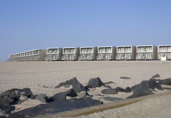 Casas de playa modernas en el Resort Hoek van Holland, Países Bajos, con arena y rocas al frente.