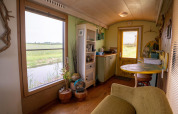 Woon- en keukengedeelte van een tiny house met zicht op veld en water, nabij de kust in Nederland.