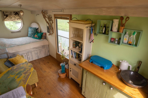 Gemütliches Tiny House in den Niederlanden mit Bett, Küchenzeile und grüner Wand nahe der Küste.