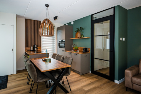 Modernes Lodge-Kücheninterieur mit Esstisch, grünen Wänden, Holzdetails und Glastür.