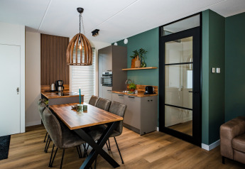 Moderne lodgekøkken med spiseplads, grønne vægge, trædetaljer, glasdør og stilfulde møbler.