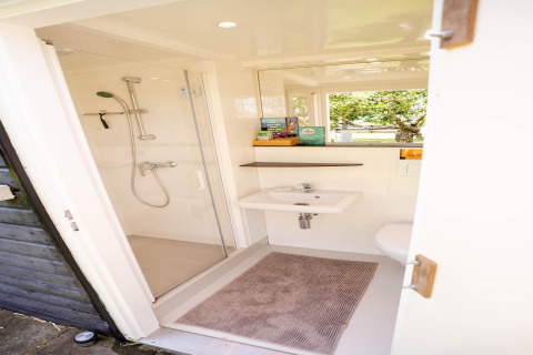 Modernes, kompaktes Badezimmer mit Dusche und Waschbecken in einem Tiny House an der niederländischen Küste.