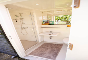 Modernes, kompaktes Badezimmer mit Dusche und Waschbecken in einem Tiny House an der niederländischen Küste.
