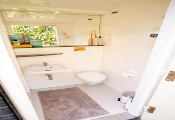 Baño moderno y luminoso en una tiny house de los Países Bajos, con inodoro, lavabo y espejo grande.