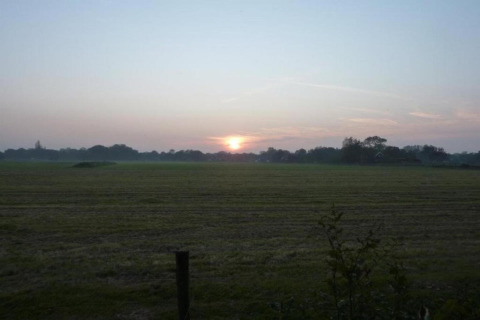 Amanecer sobre un campo abierto cerca de la costa, visto desde 'Apartment in Netherlands near the Coast', Países Bajos.