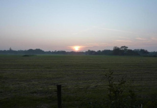 Sonnenaufgang über einer offenen Landschaft nahe der Küste, gesehen vom 'Apartment in Netherlands near the Coast'.