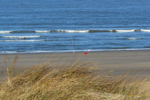 Blick auf einen leeren Strand und das Meer mit Angelausrüstung bei einer Küstenwohnung in den Niederlanden.