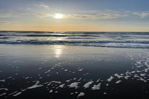 Tramonto sull’oceano presso Apartment in Netherlands near the Coast, onde e schiuma sulla riva.