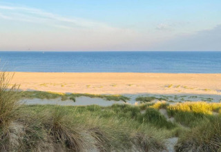 Vista desde las dunas costeras de una tranquila playa de arena y mar azul cerca de la costa de Países Bajos.