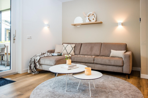 Elegantes Wohnzimmer in einer Lodge mit beiger Couch, runden Couchtischen und sanfter Beleuchtung.