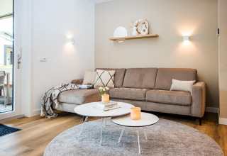Stijlvolle lodge woonkamer met beige hoekbank, moderne tafels, zacht licht en een warme sfeer.