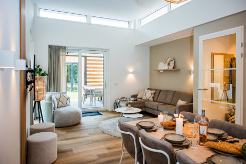 Soggiorno e zona pranzo di un lodge moderno con divano, dettagli decorativi e porte in vetro sul patio.