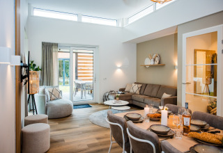 Moderne lodge-stue med spiseområde, sofa, elegante dekorationsgenstande og glasdøre til terrasse.