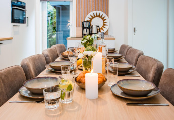 Beautifully set dining table at a lodge with dishes, glasses, candles, and a fresh flower centerpiece.