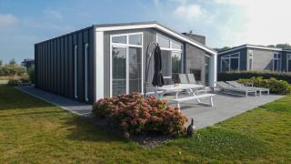 Lodge moderno en Water Resort Oosterschelde 13 con terraza amueblada, jardín y amplias ventanas.