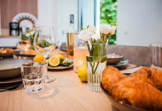 Et hyggeligt morgenbord på en lodge med friske citroner, croissanter, blomster og glas på bordet.