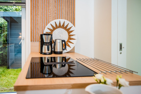 Moderne Küchenzeile mit Kaffeemaschine, Wasserkocher und dekorativem Teller in einer Lodge mit Gartenausblick.