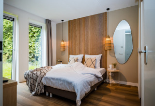 Moderne slaapkamer in vakantiewoning bij bos in Voorthuizen, Nederland, met tweepersoonsbed en natuurlijke details.