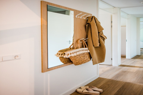 Specchio riflette ingresso con cappotto, borsa di paglia e sandali in casa vacanze a Voorthuizen vicino al bosco.
