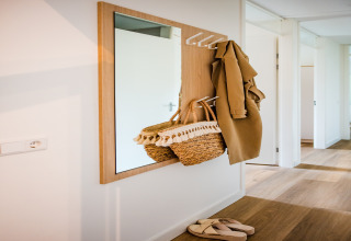 Specchio riflette ingresso con cappotto, borsa di paglia e sandali in casa vacanze a Voorthuizen vicino al bosco.