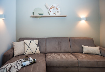 Moderne zithoek bij Holiday home in Voorthuizen nabij het bos met grijze zetel en wanddecoratie.