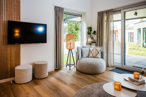 Soggiorno moderno in una casa vacanze a Voorthuizen, Paesi Bassi, con ampie finestre e arredi eleganti.