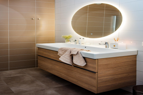Bagno moderno con mobile in legno, doppio lavabo, grande specchio ovale e luce soffusa a Voorthuizen.