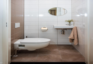 Bagno moderno nella casa vacanze a Voorthuizen con wc sospeso, lavabo e specchio, Paesi Bassi.