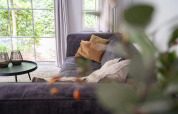 Cozy living room at Heivlinder Comfort 4+2p lodge in the Netherlands, with sofa, cushions and window view.