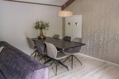 Gezellige eethoek bij Heivlinder Comfort 4+2p in Nederland, met zes stoelen, tafel en bloemenvaas.