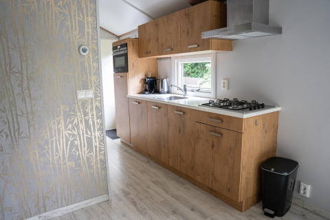 Moderne keuken in Heivlinder Comfort 4+2p lodge in Nederland met houten kasten en gasvuur.
