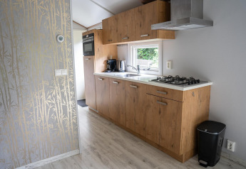Modern kitchen at Heivlinder Comfort 4+2p lodge in the Netherlands with wooden cabinets and gas stove.