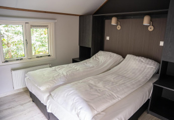 Bedroom at Heivlinder Comfort 4+2p lodge in the Netherlands, featuring twin beds, a window, and modern decor.
