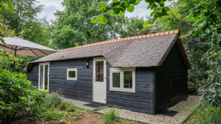 Gemütliche Heivlinder Comfort 4+2p. Lodge mit Strohdach, schwarzer Holzfassade im Wald gelegen.