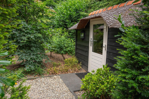 Ingang van een gezellige lodge met rieten dak, omgeven door groen in Nederland.