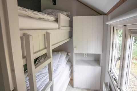 Smalle kamer in Heivlinder Comfort 4+2p lodge in Nederland met stapelbed, kast en raam.