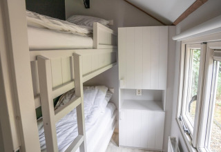 Smalle kamer in Heivlinder Comfort 4+2p lodge in Nederland met stapelbed, kast en raam.