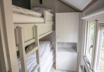 Narrow room in Heivlinder Comfort 4+2p lodge in the Netherlands with bunk bed, closet, and window.