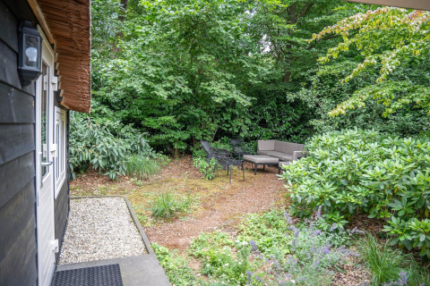 Gezellige tuinzetel met meubilair in het groen bij Heivlinder Comfort 4+2p lodge in Nederland.