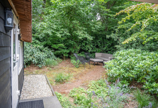 Gezellige tuinzetel met meubilair in het groen bij Heivlinder Comfort 4+2p lodge in Nederland.