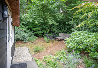 Cozy garden seating area with outdoor furniture surrounded by greenery at Heivlinder Comfort 4+2p lodge, Netherlands.