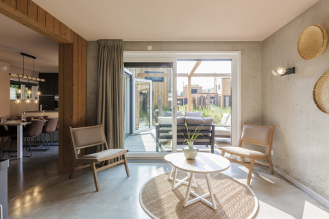 Modern living room at Noordzee Resort Vlissingen 3 with large windows, wood furniture, and patio access.