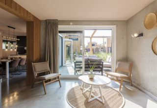 Modern living room at Noordzee Resort Vlissingen 3 with large windows, wood furniture, and patio access.
