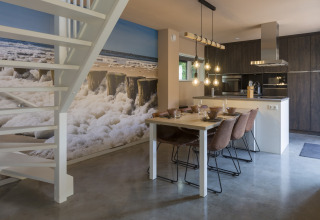 Modern dining area and kitchen in a beach house, large ocean mural, Noordzee Resort Vlissingen, Netherlands.