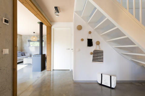 Bright modern entryway with staircase, wall hooks, bags, and a view into the living room at Noordzee Resort Vlissingen.